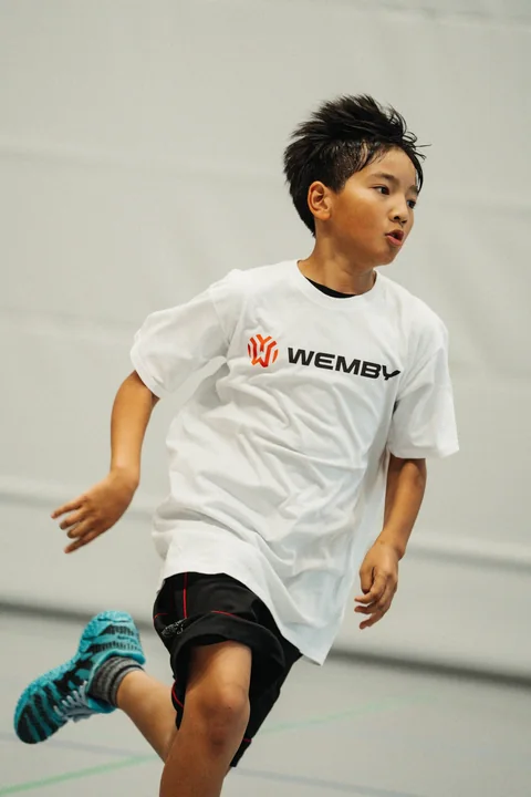 Junge im WEMBY-Shirt sprintet mit dem Ball