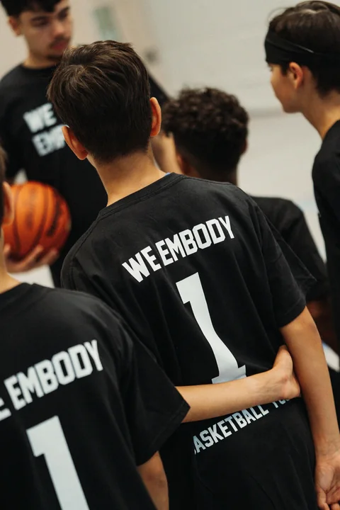 Kinder in schwarzen „We Embody“-Shirts